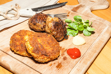 Zwei Sorten Frikadellen angerichtet auf Holzbrett