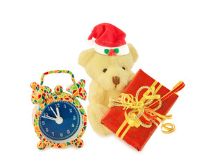 Teddy bear Santa with gift and alarm clock on white.
