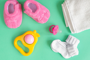children's clothes and baby booties on green background