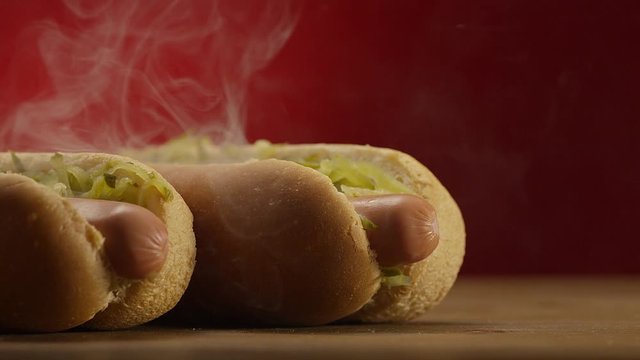 Appetizing steaming hot dog on red background. Shot on RED EPIC DRAGON Cinema Camera.