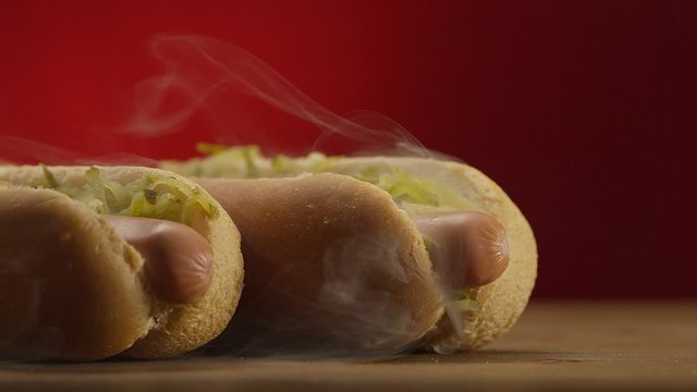 Appetizing steaming hot dog on red background. Shot on RED EPIC DRAGON Cinema Camera.