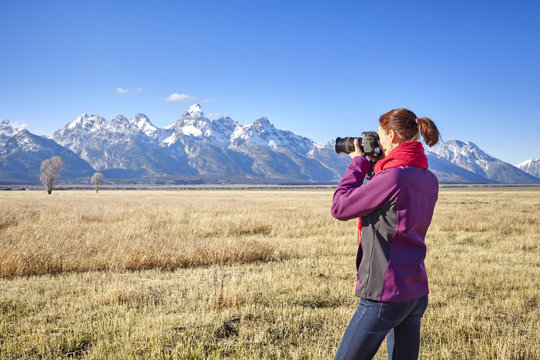 Female fit hiker taking pictures with DSLR camera in the Grand Teton National Park, Wyoming, USA.