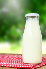 Milk bottle on wooden and blur nature background.