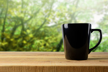 Black mug on wooden and blur background. © Ubonwan