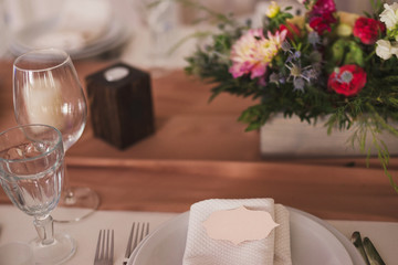 floral decoration and name card on the plate on the table at wedding reception