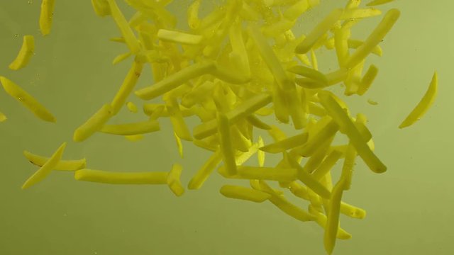 Many potato fries falling on oil. Shot on RED EPIC DRAGON Cinema Camera.
