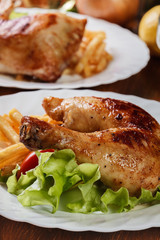 Roasted chicken legs with french fries and lettuce