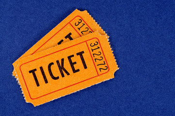 Orange ticket stub two pair for raffle movie or theater entrance admission isolated on a blue background photo