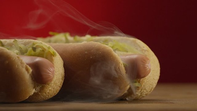 Appetizing steaming hot dog on red background. Shot on RED EPIC DRAGON Cinema Camera.