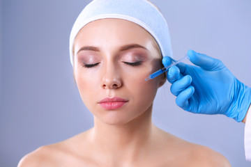 Cosmetic injection the pretty woman face. Isolated on gray background