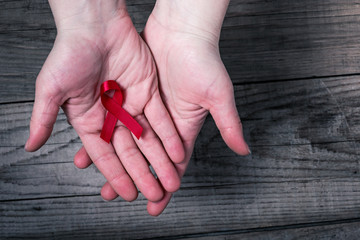 Red ribbon on palms - awareness and support for people living with HIV