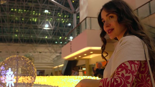 Beautiful brunnete young woman looking at beautiful Christmas lights at the shopping mall. 4K video