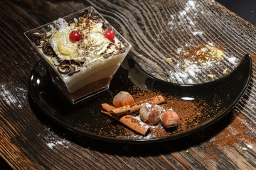 creamy cake in black Yin Yang plate on wooden table