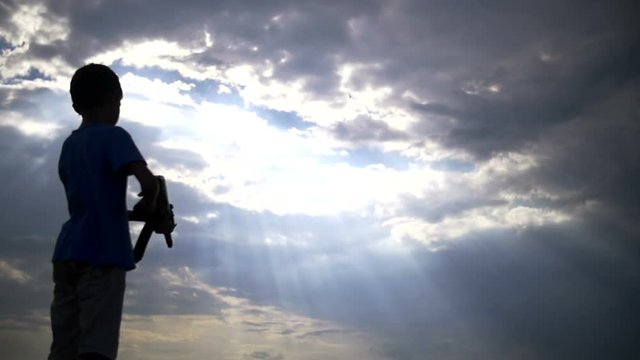 silhouette boy with a gun at sunset on the background of clouds, ak 47