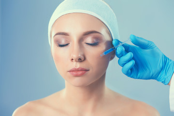 Cosmetic injection the pretty woman face. Isolated on gray background