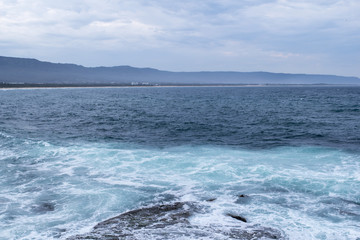 Clear blue waters of the ocean strip of beach and mountains on the horizon