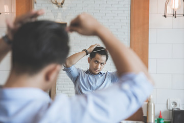 man combing his hair after having a cut at barbershop