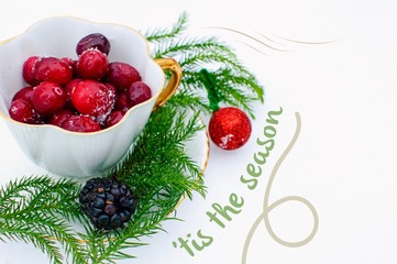 Christmas Card with Words 'tis the season with vintage tea cup and cranberries in fresh snow