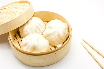 Steamed pork buns (chinese dim sum) in bamboo basket, serve with chopsticks on a white background,...