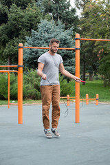 muscular sports man skipping rope outside