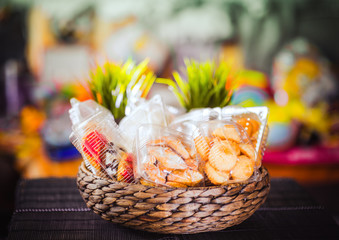 Plastic disposable containers with cookies and pastries in a wicker wooden basket on a motley, colored background