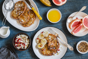 Breakfast - caramel french toast with banana, cottage cheese with granola and pomegranate, fresh grapefruit on a blue background. Top view, flat lay