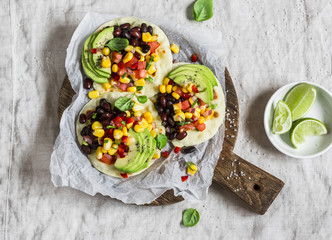 Spicy bean tortillas with corn salsa and avocado  on a rustic cutting board on a dark background. Delicious vegetarian snack