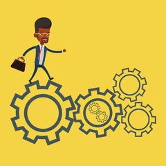 Businessman running on cogwheels.