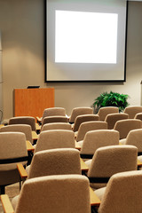close up on auditorium room with projector screen and rows of seats
