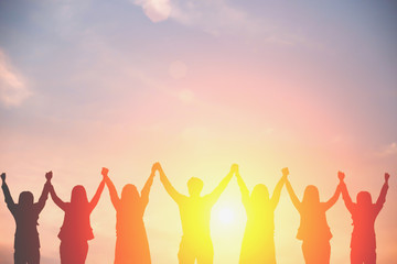 Silhouette of happy business team making high hands in sunset sky