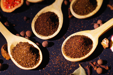 Closeup wooden rustic spoons filled up with fresh herbal tea powder, other teas and spices in background, very nice arrangements