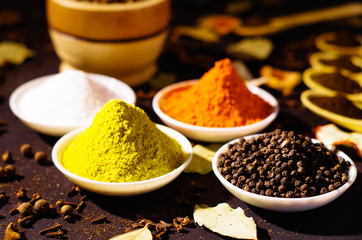 White bowls spread out with different colorful spices inside, beautiful rustic setting, spice and herbal concept