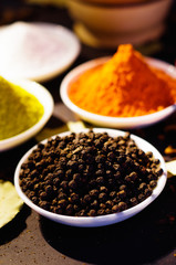 White bowls spread out with different colorful spices inside, beautiful rustic setting, spice and herbal concept