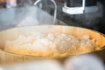 Mixing rice. Close up of cook hands mixing with long wooden spoon white rice in a wooden bowl
