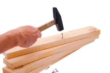 Hammer driving a nail into a wooden board against a white backgr