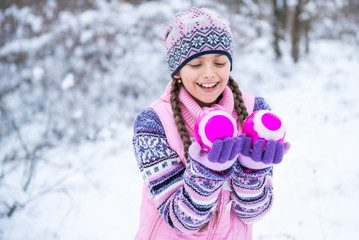 Attractive young woman in wintertime outdoor. Portrait of a beautiful teen girl holding a Christmas balls. Girl in a pink sweater winter woods on background of snow
