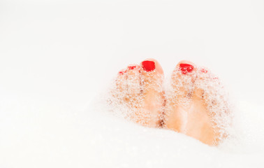 Fototapeta premium Feet with red nails soaking in spa bath
