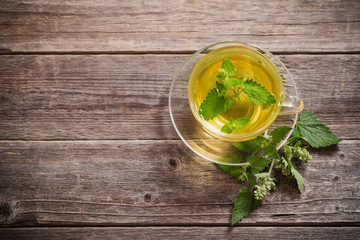 green melissa herbal tea in glass cup on wooden background