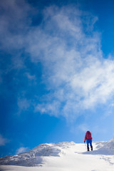 Girl with backpack walking on snow in the mountains.