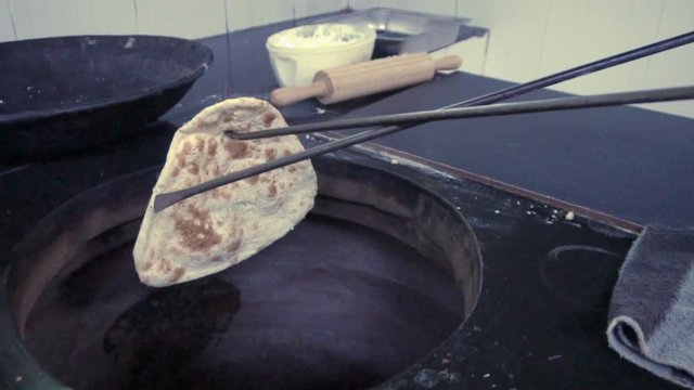 Indian chef cooking garlic naan in tandoori oven