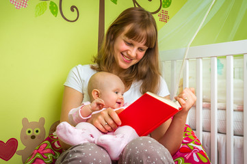 Happy mother reading a book to her baby girl