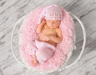 Fototapeta na wymiar lovely newborn girl in pink panties and hat in basket