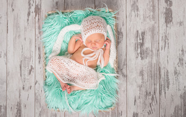 funny sleeping newborn in panties and hat on a cot
