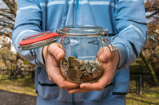 Man In Blue Sweatshirt Holding Money Jar With Coins