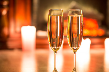 Beautiful two glasses of champagne standing on the table in the background of a blurred room with a decorated Christmas tree and candles. Soft focus. Shallow DOF