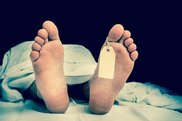 The dead man's body with blank tag on feet under white cloth