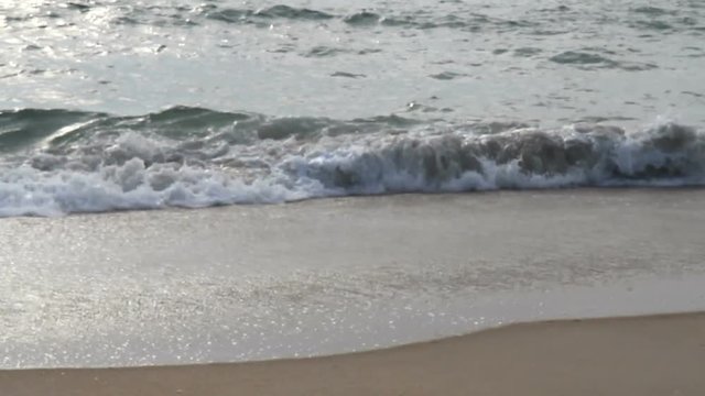 White sunlight reflects off  close-up ocean waves breaking on a beach at Nags Head on the Outer Banks of North Carolina to start a beautiful summer day in June