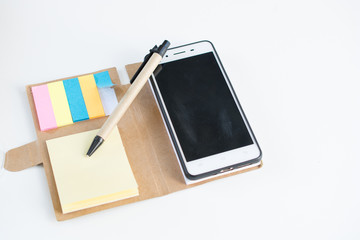Mobile phone notebook and pen on white background