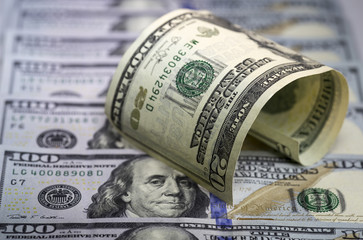 Arched twenty us dollar bill standing on lined hundred us dollar bills background. Selective focus.