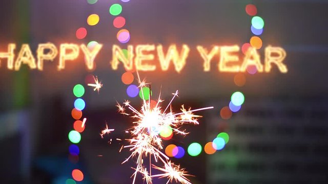 Happy New Year  inscription sparklers on a black background. Colorful lights on the background.